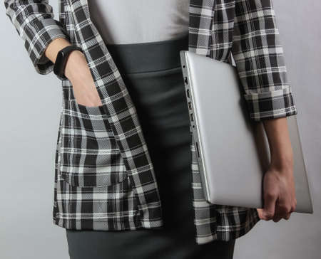 Business business woman in formal clothes holds a laptop while standing on a white background. Crop...
