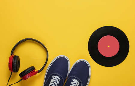 Stylish headphones, old school sneakers, vinyl record on yellow background. Retro style. 80s.  Pop culture. Top viewの写真素材