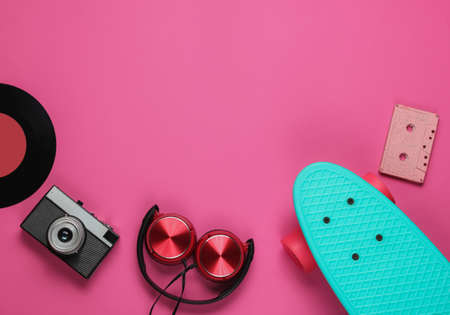 Cruiser board, headphones, film camera, audio cassette, vinyl record on pink background. Retro style. 80s. Pop culture. Copy space. Top viewの写真素材
