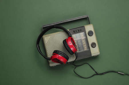 Retro radio receiver, old-fashioned wired headphones on a green background. Old  mass media. Top viewの写真素材