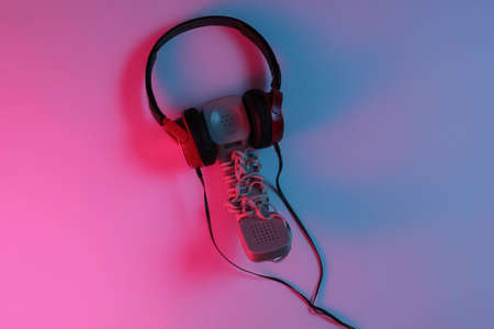 Old fashioned handset with headphones. Red-blue neon gradient light. Retro wave, pop culture. Top...