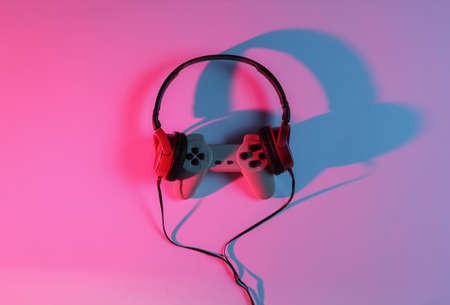 Wired headphones with gamepad. Neon blue-red gradient light. Retro wave, 80s pop culture. Top view