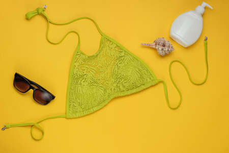 Woman's swimsuit and beach accessories on yellow background. Overhead view of woman's swimwear. Summer background, vacation on the beach. Flat lay, top view.の写真素材
