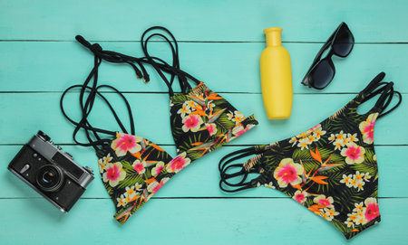 Summer fun background. Woman's swimsuit and beach accessories on blue wooden background. Overhead...