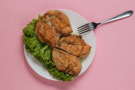 Grilled chicken breasts with lettuce on a plate on a pink pastel backgroundの写真素材