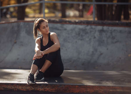 Attractive fit woman in sportswear resting while sitting in sports parkの写真素材