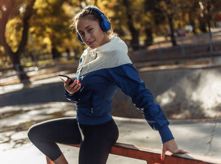 Young attractive sport woman in sportswear with headphones listens to music at sports park.の写真素材