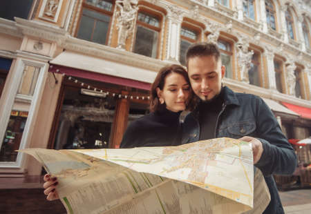 Beautiful couple on vacation using paper city map for directions. Travel vacation, leisure...