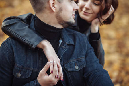 Young hugging couple of lovers on a blurry background of fallen autumn leaves in the park. Romantic, love conceptの写真素材