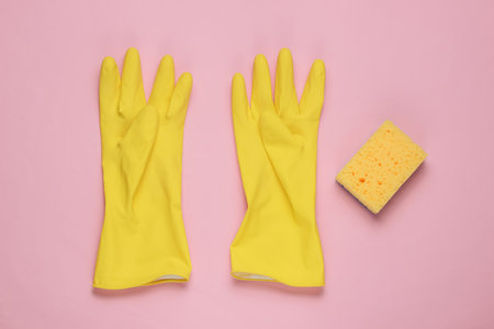 Yellow latex gloves and sponge for cleaning on pink background. The concept of cleaning. Pastel color trend. Studio shot. Top viewの写真素材