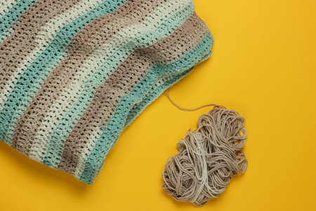 Hand knitting and skeins of thread on yellow background. Top view. Home hobbyの写真素材
