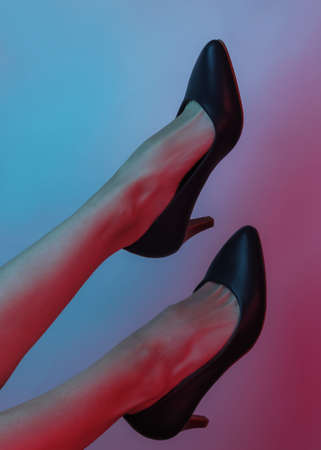 Women's legs with classic high heel shoes. Creative pop art pink blue neon color. Trendy gradient illumination. Night lightの写真素材