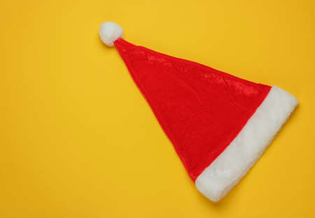 Santa hat on yellow background. New Year, Christmas minimalistic concept. Top view, studio shot.