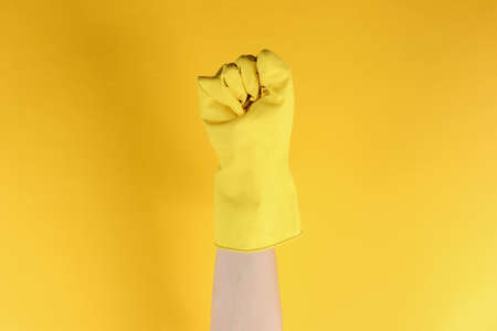 Femen symbol. Female fist in rubber gloves on a yellow studio backgroundの写真素材