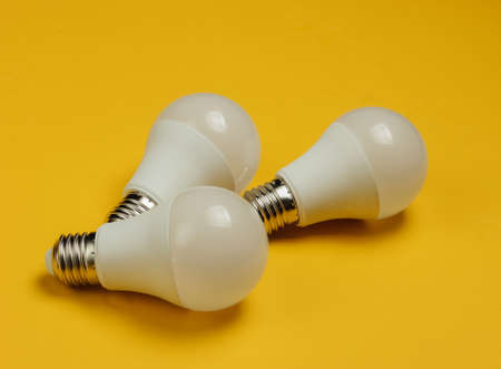 Three LED light bulbs on yellow background.の写真素材