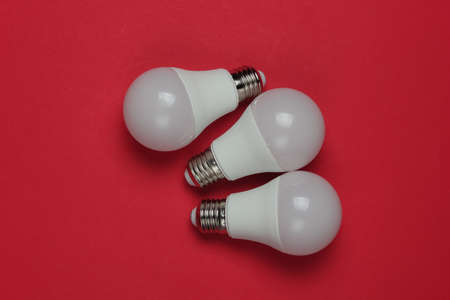Three LED light bulbs on a red background. Top view