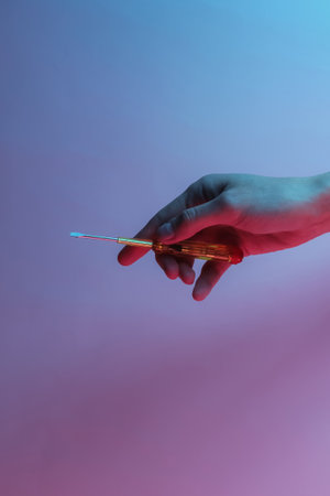 Hand holds screwdriver. Creative pop art pink blue neon color. Trendy gradient illumination. Night lightの写真素材