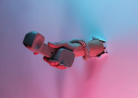 Hand wrapped in a cable holds the handset through torn hole. Creative pop art pink blue neon color....