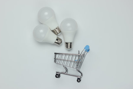 Three LED light bulbs and shopping trolley on white background. Top viewの写真素材