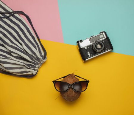 Summer background. Fun and humor. The concept of a beach holiday. Pineapple and coconut with sunglasses, beach bag on colored background. Top viewの写真素材
