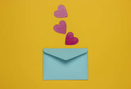 Envelope with decorative hearts on yellow background. Flat lay mockup for Valentine's day, wedding or birthday. Top viewの写真素材