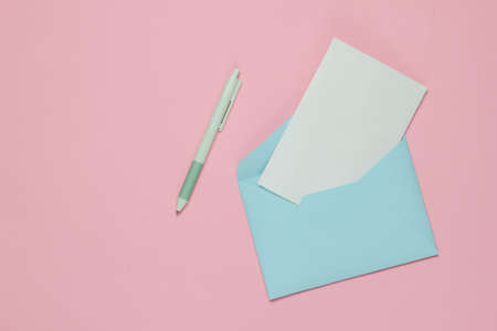 Envelope with a letter and pen on pink pastel background. Valentine's day, wedding or birthday. Top viewの写真素材