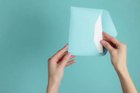Female hand holds envelope with letter on blue pastel background. Top view. Valentine's day, wedding...