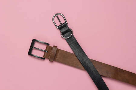 Two leather belts on pink pastel background close-upの写真素材