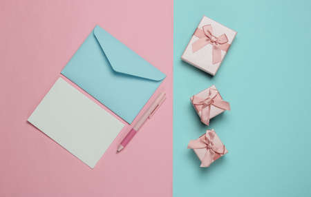 Letter to Santa. Envelope with letter and pen, boxes of gifts on pink blue background. Christmas Flat lay. Top viewの写真素材