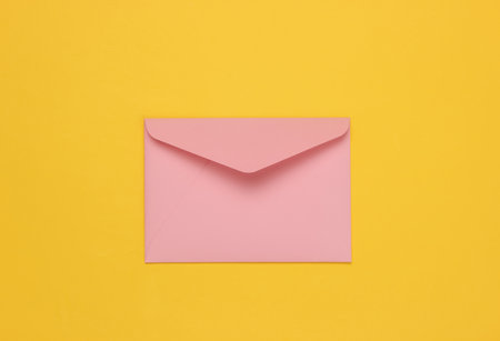 Envelope pink pastel color on yellow background. Flat lay mockup for valentines day, wedding or birthday. Top viewの写真素材