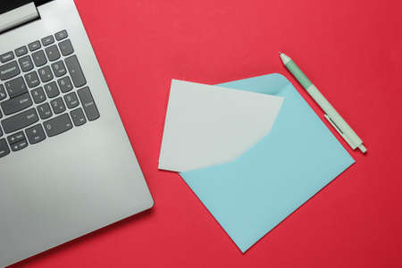 Laptop and envelope with letter on red background. Valentine's day. Top viewの写真素材