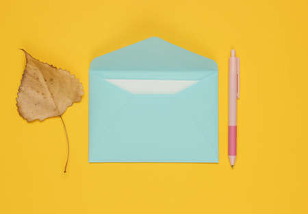 Envelope with a letter, pen, autumn leaf on a yellow background. Letter of love.