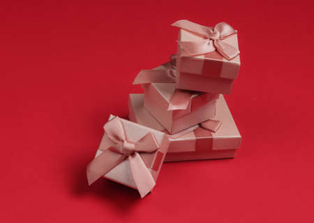 Stack of gift boxes with bows on red studio background. Composition for christmas, birthday or wedding.の写真素材