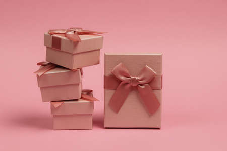 Stack of Gift boxes with bows on pink pastel background. Composition for christmas, birthday or wedding.の写真素材