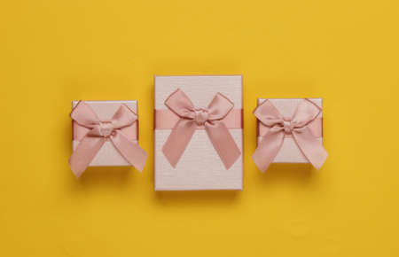 Gift boxes with bow on yellow background. Composition for christmas, birthday or wedding. Top view