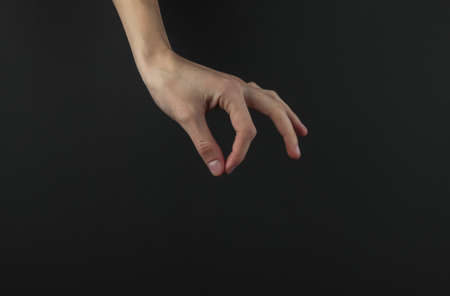 Female hand with fingers holds something on black background.の写真素材