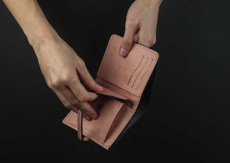 Female hands open pink leather purse on a black background