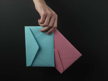 Female hand holds envelopes on a black backgroundの写真素材
