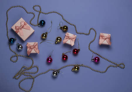 Gift boxes, Christmas balls, garlands on purple background. Christmas concept. Top view