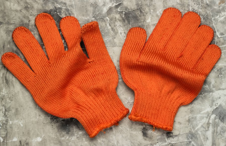 Orange work gloves on a gray concrete background