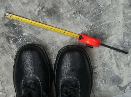 Work leather shoes and tape measure. Industrial working tools and instruments, safety equipmen on gray concrete background. Top viewの写真素材