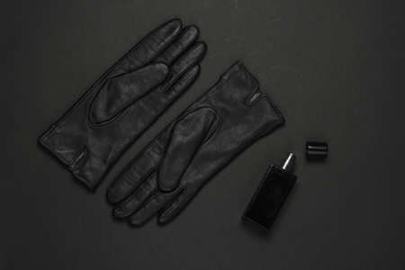 Women's fashion accessories on a black background. Leather gloves, perfume bottle. Top viewの写真素材
