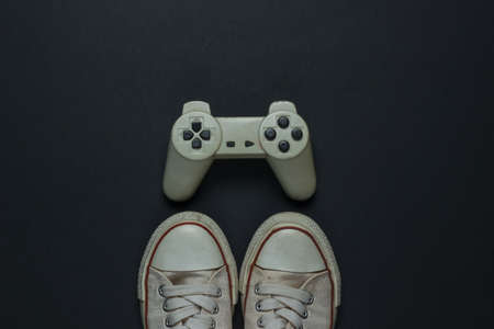 Retro old sneakers and gamepad on black background. 80s. Top view