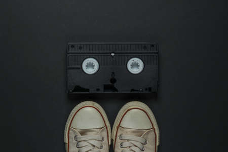 Retro old sneakers and video cassette on black background. 80s. Top viewの写真素材