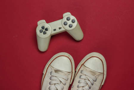 Retro old sneakers and gamepad on red background. 80s. Top view