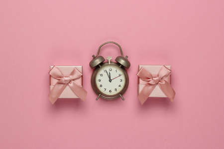 Retro alarm clock and gift boxes with bow on pink pastel background. 11:55 am. New Year, Christmas concept. Top viewの写真素材