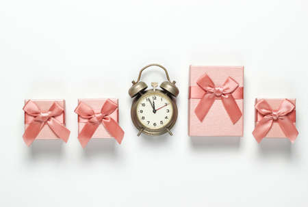 Retro alarm clock and gift boxes with bows on white background. 11:55 am. New Year, Christmas concept. Top viewの写真素材