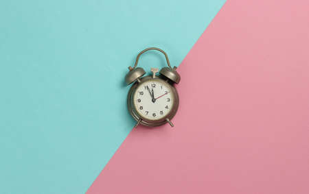 Retro alarm clock on pink blue pastel background. 11:55 am. New Year. Top viewの写真素材
