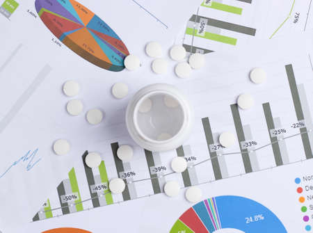 Medical statistics and analytics. Bottle of pills with graphs and charts.の写真素材