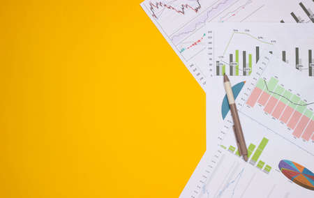 Pen with graphs and charts on a yellow background. Business plan, financial analytics, statistics....